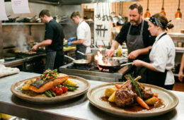Küchenbrigade an der Pass-Durchreiche eines Restaurants, mehrere Köche bereiten Teller für den Service vor.