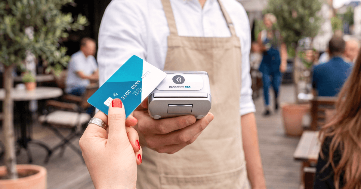 Detailaufnahme einer EC-Karte, die auf ein NFC-Terminal gehalten wird, geringe Tiefenschärfe, lebendige Komposition, warme Farben.