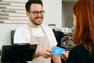 Gastronom überreicht Gast einen Wertgutschein an der Kasse, gedruckt über das orderbird Gutscheinsystem