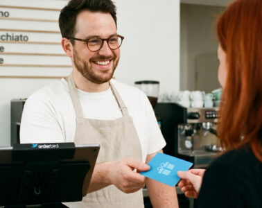 Gastronom überreicht Gast einen Wertgutschein an der Kasse, gedruckt über das orderbird Gutscheinsystem