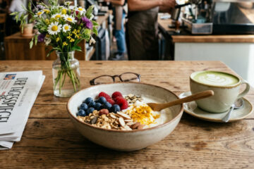 Functional Food Bowl mit Heidelbeeren, Chiasamen und Kurkuma in einem Café-Setting.